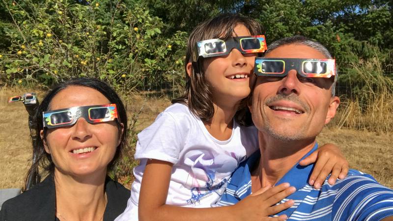A family wearing eclipse glasses.