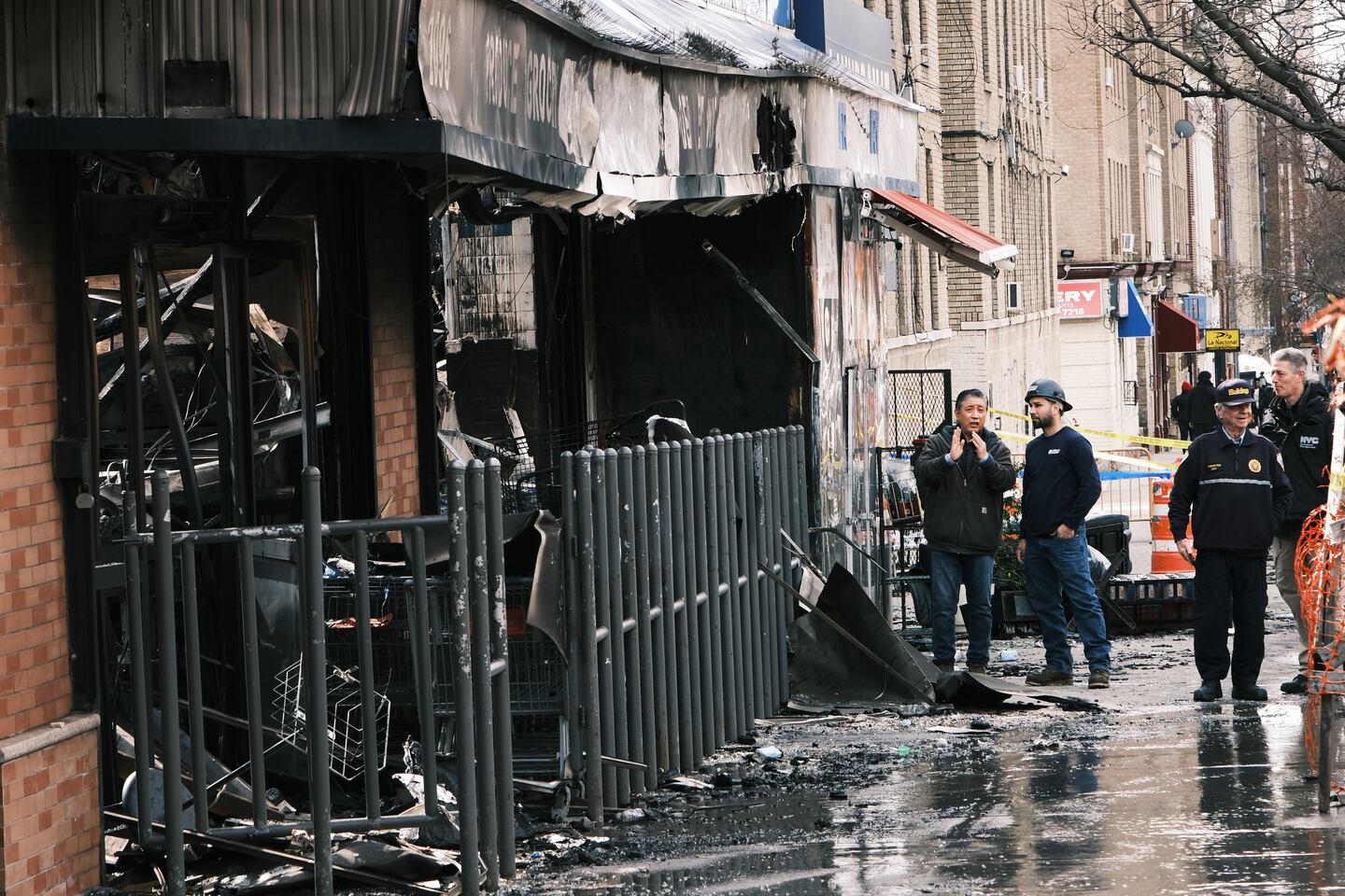 NEW YORK, NEW YORK - MARCH 06: Fire officials and others gather outside of a Bronx supermarket the day after a 5-alarm fire tore through a market that fire officials are blaming on a faulty lithium-ion battery on March 06, 2023 in New York City. While there were no fatalities in the blaze, numerous people were injured and it took approximately 200 firefighters to bring the fire under control. Fires from these batteries, which are increasingly used in scooters and bicycles, are increasing in number across the nation. The FDNY responded to dozens of such fires last year alone as the devices become popular for both work and recreation.