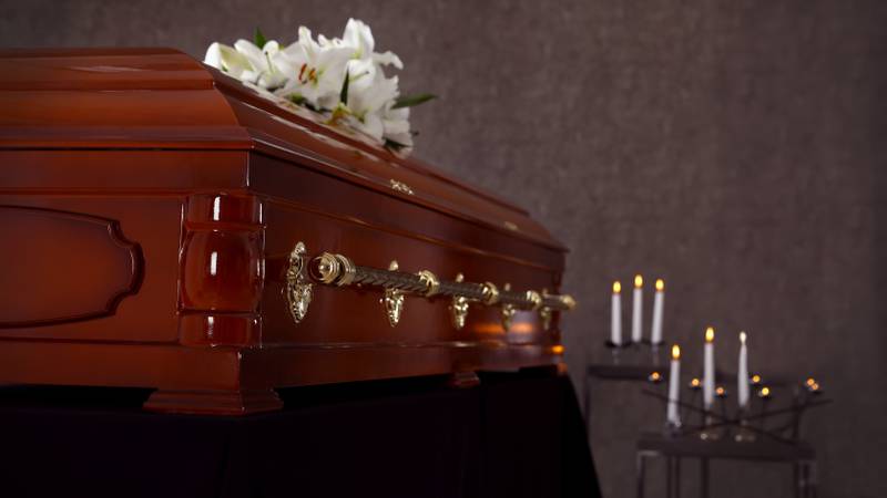 Wooden casket with white lilies in funeral home